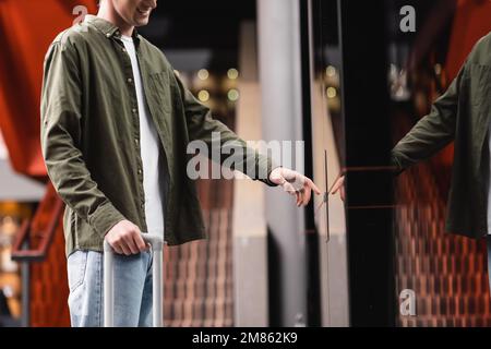 partial view of smiling man pressing elevator call button in contemporary hotel,stock image Stock Photo