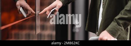 cropped view of man holding mobile phone and pressing call button of elevator in hotel, banner,stock image Stock Photo