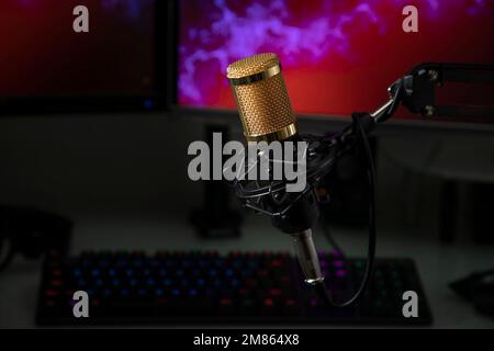 Professional microphone with gamer workstation in the background and headphones. Stock Photo
