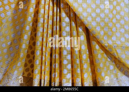 Artistic variety shade tone colors ornaments patterns, closeup view of stacked saris or sarees in display of retail shop. Stock Photo