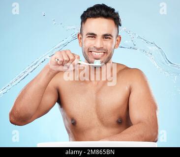 Teeth, dental care and water splash, man with toothbrush and toothpaste on blue background with smile on face. Morning routine, healthcare and fresh Stock Photo