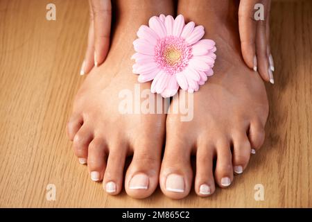 Natural woman and manicure with flower on feet for luxury cosmetic treatment with spa pedicure nails zoom. Healthy skincare of black woman with daisy Stock Photo