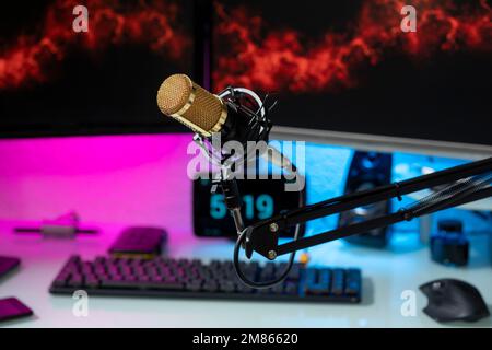 Professional microphone with gamer setup in the background and colored lights. Stock Photo