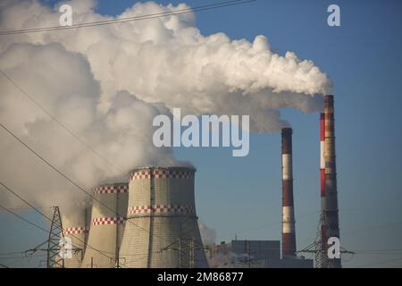 CHP cooling towers from which smoke is coming out against blue sky Stock Photo