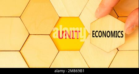 Unit economics symbol. Concept words Unit economics on wooden puzzles. Beautiful yellow table yellow background. Businessman hand. Business and unit e Stock Photo