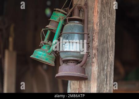An old kerosene lamp hanging from a wooden beam or window. Stock Photo