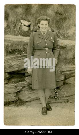 Original WW2 era postcard of pretty woman serving in the Auxiliary Territorial Service (ATS) wearing her service dress, dated May 1945, Port St Mary, Isle of Man. Possibly she is from the Special Operators Training Battalion based here from 1943 to train ATS women as intercept wireless operators for Bletchley Park amongst others. Young lady's of the ATS did:  three weeks' basic training at Queens Camp, Guilford. then posted to Douglas, Isle of Man, for four months to train as a Special Wireless Operator, Royal Corps of Signals. Stock Photo