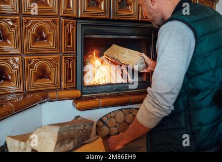 Man putting wood logs in the home mantel fire.Home sweet home and winter countryside holidays concept image Stock Photo