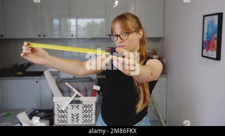 repair home concept, young woman with a measuring tape in the kitchen and instruments for renovation in the background. High quality photo Stock Photo