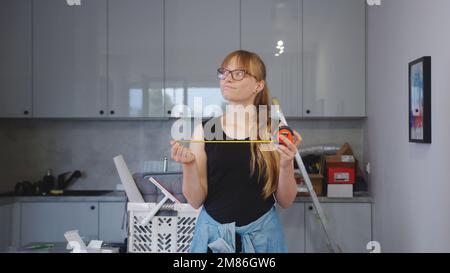nice looking Caucasian woman in casual clothes holding measuring tape, looking up and thinking, repair concept. High quality photo Stock Photo