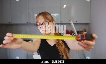 Caucasian woman measuring something with a measuring tape and thinking in the kitchen. High quality photo Stock Photo