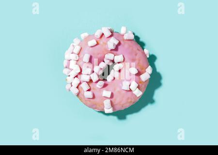 Delicious glazed donut with marshmallows on blue background Stock Photo