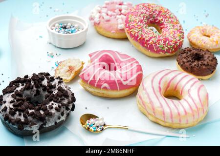 Parchment with different delicious donuts on blue background Stock Photo