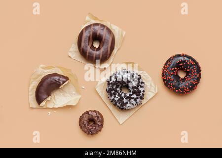 Parchments with different delicious donuts on beige background Stock Photo