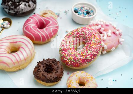Parchment with different delicious donuts on blue background Stock Photo
