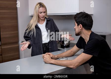 Young Caucasian Couple Have Disagreement in Kitchen at Home. Quarrel in Young Family. Angry Wife. Divorce Concept. Upset Husband. Relationship between Stock Photo