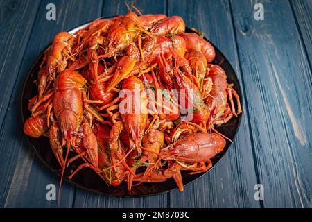 Lots of boiled crayfish. Boiled crayfish in a black plate on a black wooden background. Stock Photo