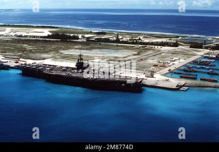 Aerial port quarter view of the Forrestal Class, Aircraft Carrier USS SARATOGA (CV 60) tied up at the British Naval Base at Diego Garcia. The ship stopped at the British Protectorate during her 1987 deployment. Visible on the flight deck as F-14A Tomcats, A-6E Intruders and E-2B Hawkeye aircraft. Base: Diego Garcia Country: British Indian Ocean Territory (IOT) Stock Photo