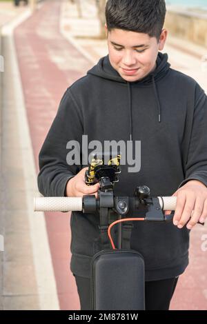 smiling young teenager riding an electric skateboard and using smart phone application E-Mobility urban leisure concept Stock Photo