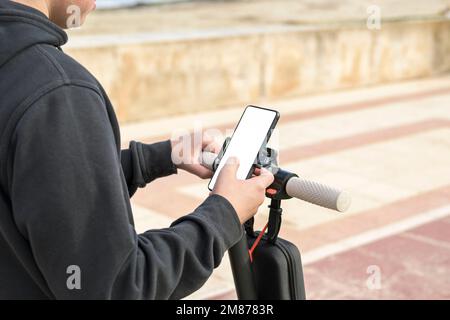 Young cheerful man with e-scooter using scooter-sharing system application on his smartphone Stock Photo