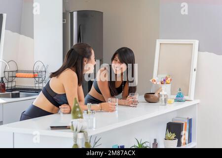 A woman smiles while chatting with her friend after doing yoga exercises. Stock Photo
