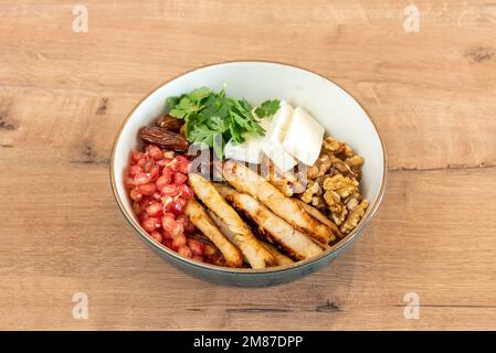 A Persian-style salad with grilled chicken, california walnuts, cheese and dates, pomegranate seeds and cilantro Stock Photo