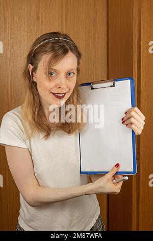 Young beautiful woman holding clip board with empty white paper in her hands Stock Photo