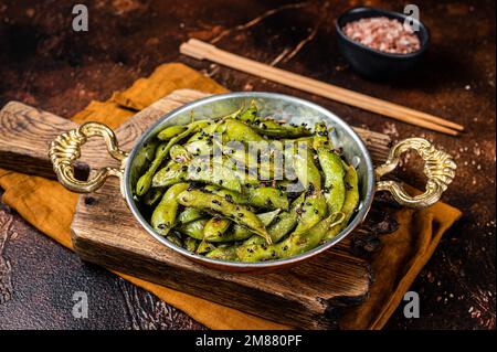 Roasted green Edamame Soy Beans with sea salt and sesame seeds in a skillet. Dark background. Top view. Stock Photo