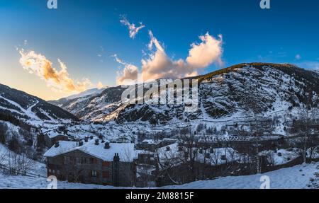 Panoramic view on El Tarter village with clouds and mountains illuminated by sunset and valley in deep shadow. Ski winter holidays, Andorra, Pyrenees Stock Photo
