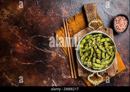 Roasted green Edamame Soy Beans with sea salt and sesame seeds in a skillet. Dark background. Top view. Copy space. Stock Photo