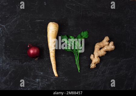 Red onion, parsnip root, ginger and parsley on black textured background. Minimal composition. Top view, flat lay. Stock Photo