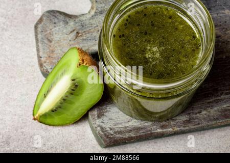 Homemade kiwi jam in a jar and kiwi slyces on concrete background with copy space Stock Photo