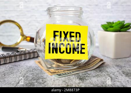 The word fixed income in English written on a piece of paper over a blue calculator and a pen in the composition. Economy and investments. Stock Photo