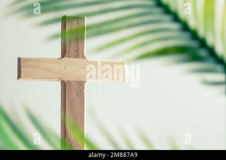 Simple wood Christian cross with palm frond leaves on a white background with copy space Stock Photo