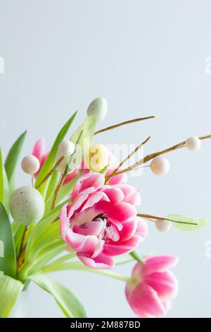 Fresh bouquet of pink tulips with a sprig of easter eggs on a white background with copy space Stock Photo