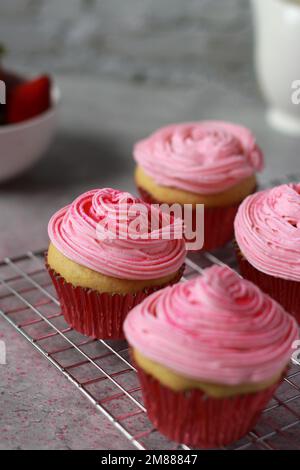 Close up of vanilla muffins with buttercream frosting on top, grey marble table  Stock Photo