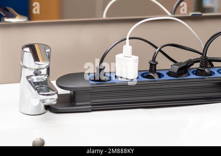 Close up of a plug in an electrical socket at bathroom with many connections and electrical overload Stock Photo