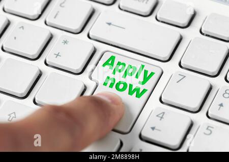 Close-up of a finger pressing a laptop keyboard key displaying the word "Apply Now" Stock Photo