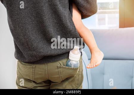 Rearview shot of an unrecognizable single father with a bottle in his pocket at home Stock Photo