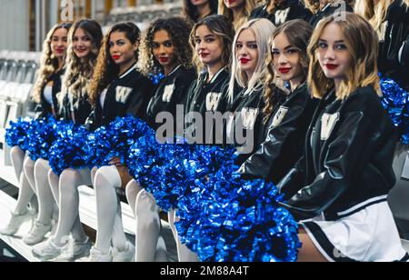Cheerleaders sitting on chairs in a row dressed in mini-skirts holding pom-poms.  Stock Photo