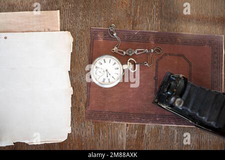 Top view of a old camera and old pocket watch on old book and desk Stock Photo