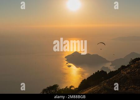 Paragliding from Babadag Mountain at Sunset overlooking Oludeniz near Fethiye in Turkey Stock Photo