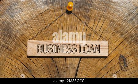 Business loan text. It is written on a wooden surface. The background is white Stock Photo