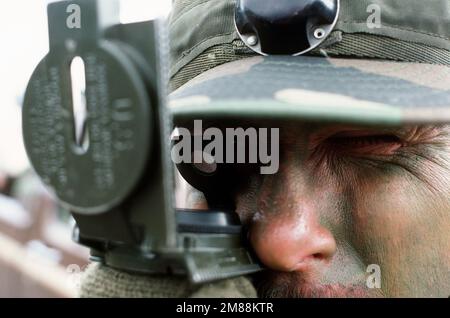 Close-up view of airman wearing a helmet, with MILES (Multiple Integrated Laser Engagement System) gear attached, sights through his compass during a training exercise. Exact Date Shot Unknown. Country: Unknown Stock Photo