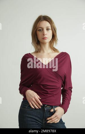 Studio photo of young female model wearing burgundy shirt made from organic cotton. Comfortable sustainable fashion. Stock Photo