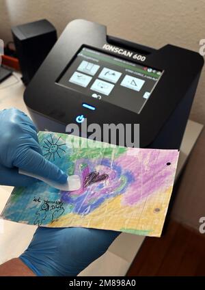 Bruchsal, Germany. 10th Jan, 2023. A sample is taken from a child's painting with a so-called swab at Bruchsal Prison (JVA). The painting, whose paper is impregnated with synthetic cannabinoid, comes from prisoner mail and was intended for an inmate. By means of an ion scanner (in the background), which can detect drugs, this was determined. (to dpa 'Drug scanners' in prisons strike around 150 times') Credit: Uli Deck/dpa/Alamy Live News Stock Photo