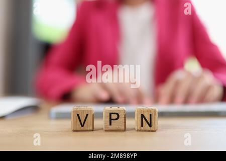 Letters VPN on wooden cubes - Virtual Private Network and Internet user works on computer in background. Stock Photo