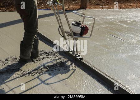 In construction new driveway machine is used to align fresh concrete layer of compacted layer Stock Photo