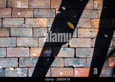 Silhouette of two legs of a man on old multicolor bricks paving stones footpath pattern on sidewalk outdoors as brickwork weave texture or abstract st Stock Photo