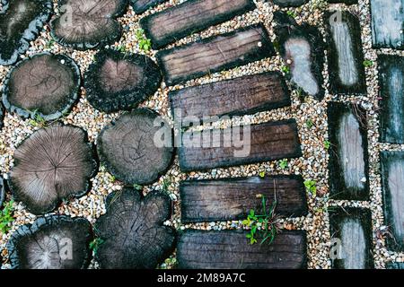 Top view of artificial wooden plate walkway made from concrete on pebble and green grass in the garden. Path in the park. Artificial wood pattern used Stock Photo